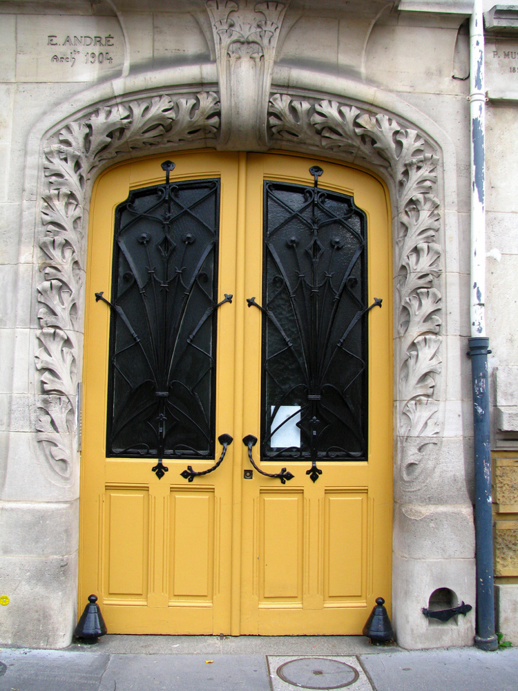 Fachada de pedra com folha dupla em ferro forjado em estilo art nouveau com porta antiga amarela