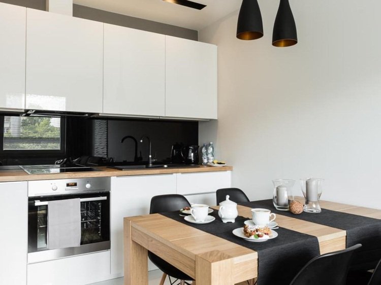 cozinha de uma fileira em branco alto brilho com fundo de vidro preto e bancada de madeira