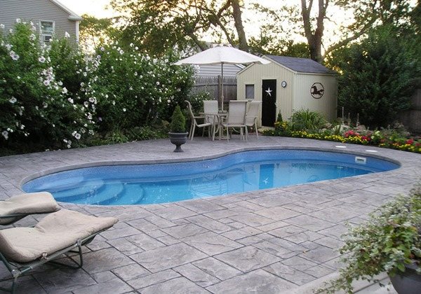 Casa com jardim, piso de pedra, guarda-sol e área da piscina