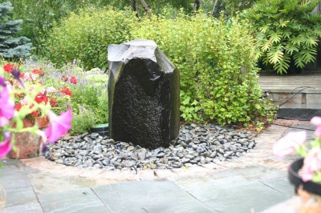 Jardim de loteamento fonte de pedra piso de cascalho flores perenes