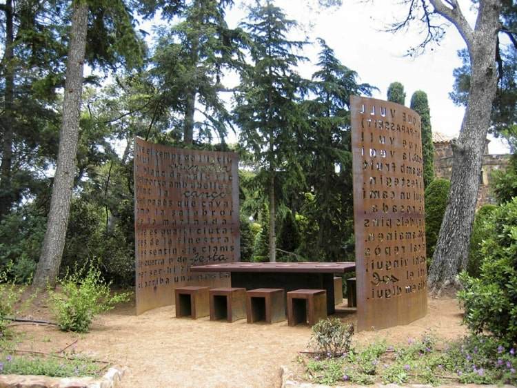 Sala de jantar feita inteiramente de corten com mesa, bancos e telas de privacidade