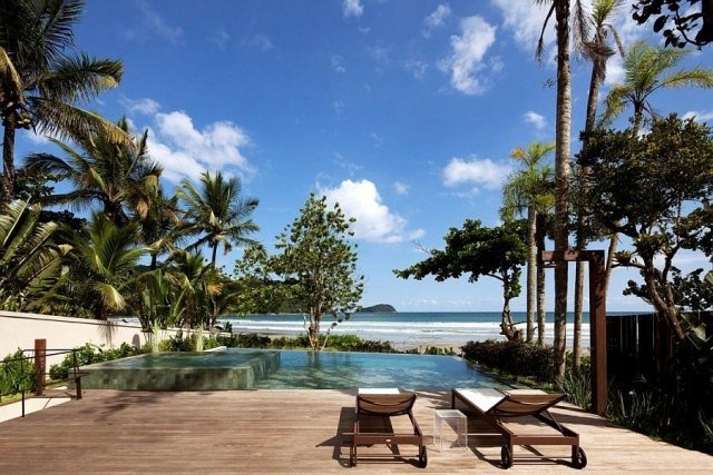 villa de praia terraço ao ar livre piscina infinita palmeiras espreguiçadeiras de madeira