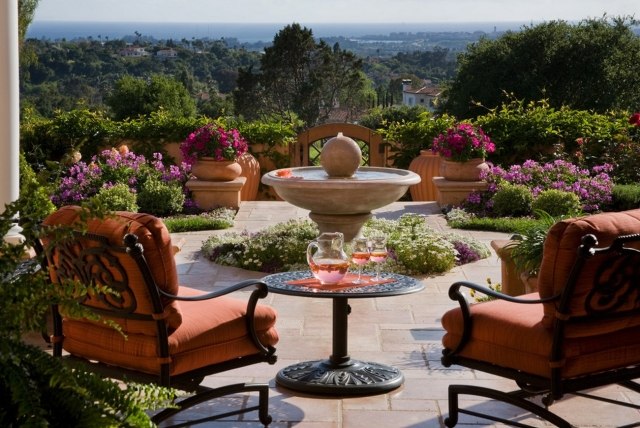 terraço ideias toscana flair fonte pedra redonda móveis de ferro flores