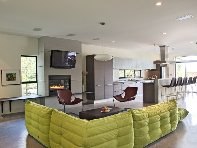 sala cozinha sofá verde aberto lareira no meio da sala