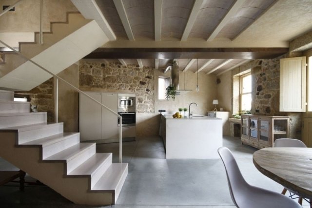 cozinha com mesa reformada parede de pedra piso de concreto polido escadas