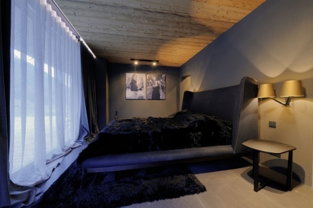 quarto de luxo, pequena cama preta, teto de madeira, gradines transparentes