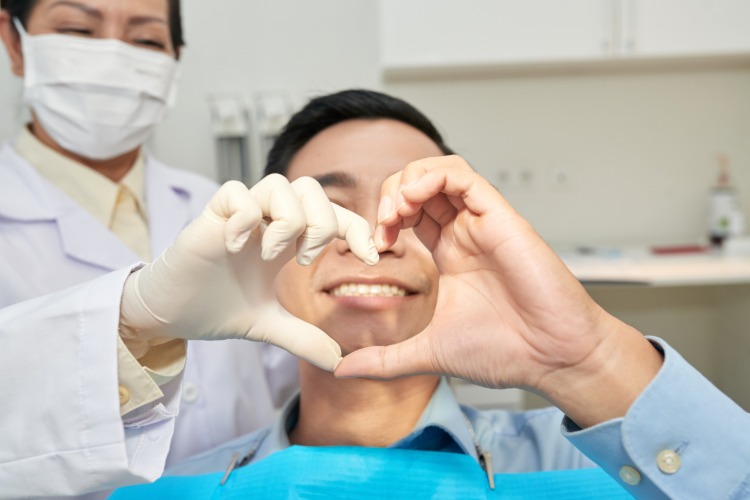 Paciente feliz e dentista mostrando gesto de coração com as mãos durante a visita #dentista
