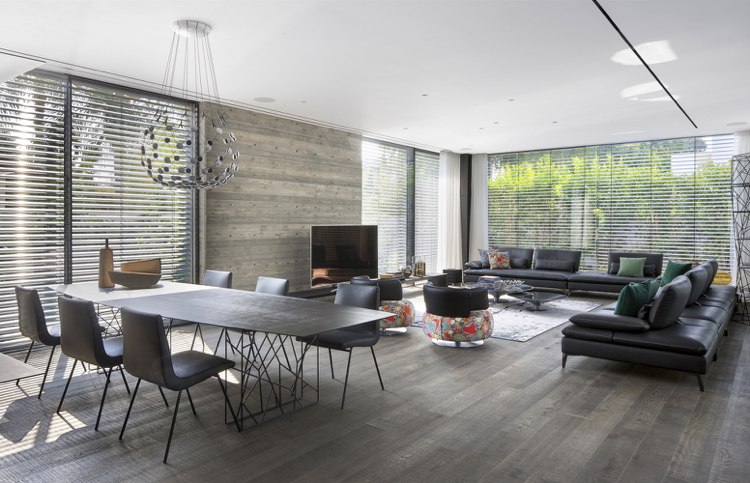 Sala de estar com área de jantar e sofá de couro e duas poltronas em cores de destaque