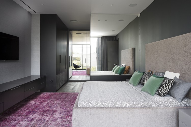 Quarto com paredes em cinza ardósia e carpete em almofadas rosa e verdes na cama
