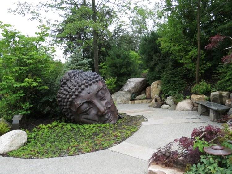 asian-garden-decoration-buddha-statue-metal-bench-stone-green-trees-garden-pedregulho
