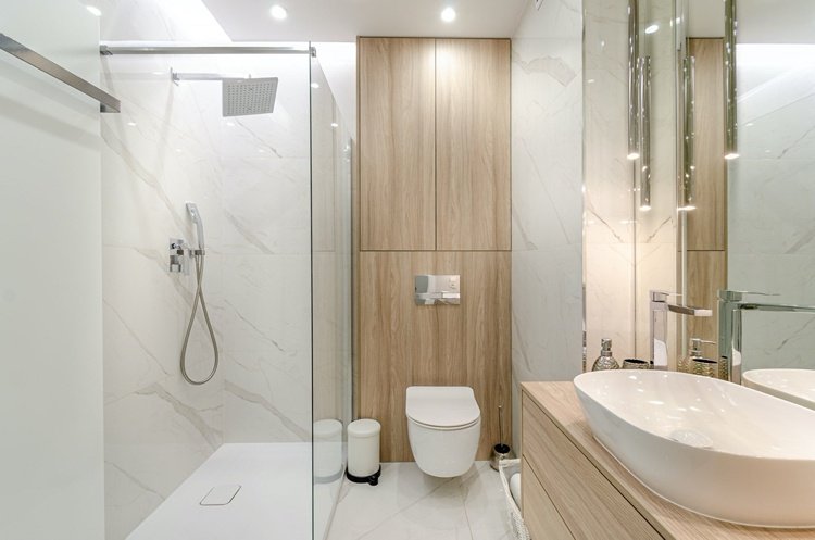 banheiro com aparência de mármore bege branco e combinação de madeira