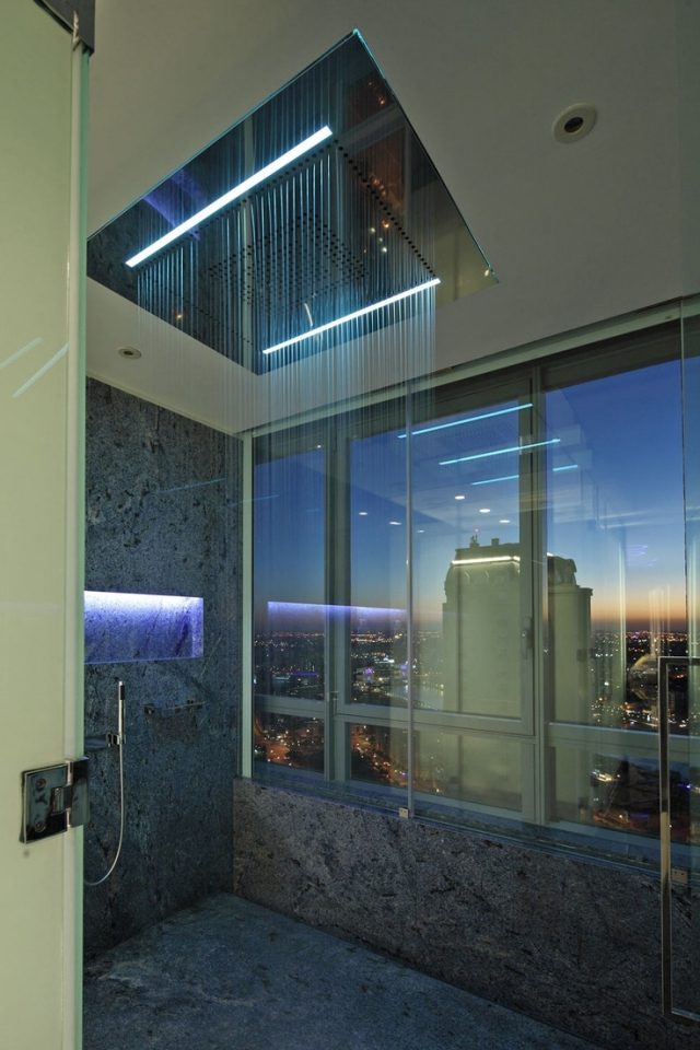 banheiro moderno com chuveiro com efeito de chuva e iluminação com vista da cidade