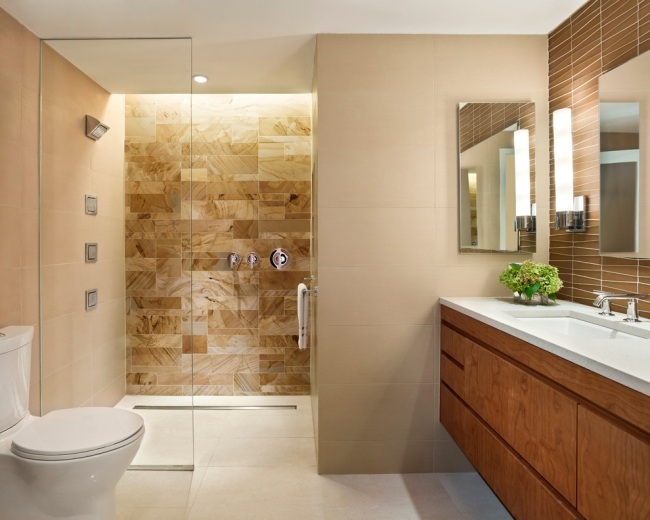 Gabinete de base de madeira com azulejos de banheiro em marrom creme de chuveiro com parede de vidro