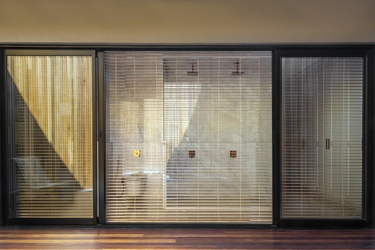 A casa de banho com frentes de janela de correr tem cortinas como telas de privacidade