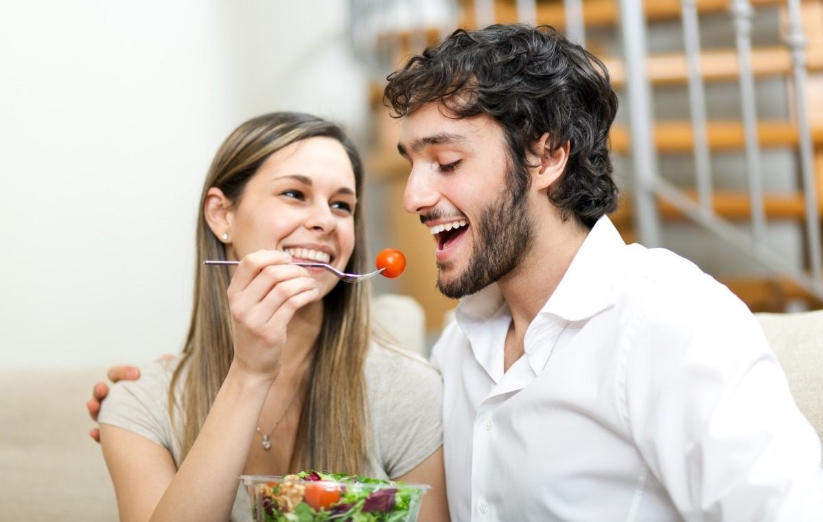 mulher entrega ao parceiro tomates cereja da saladeira para melhor absorção de carboidratos