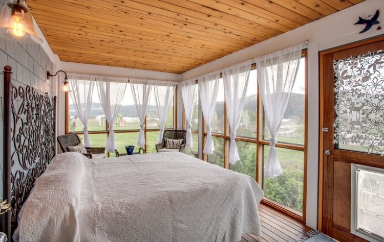 estilo boêmio-quarto-branco-madeira-teto-cama de metal-brincalhão-ornamentos-cabeceira-janela-vista