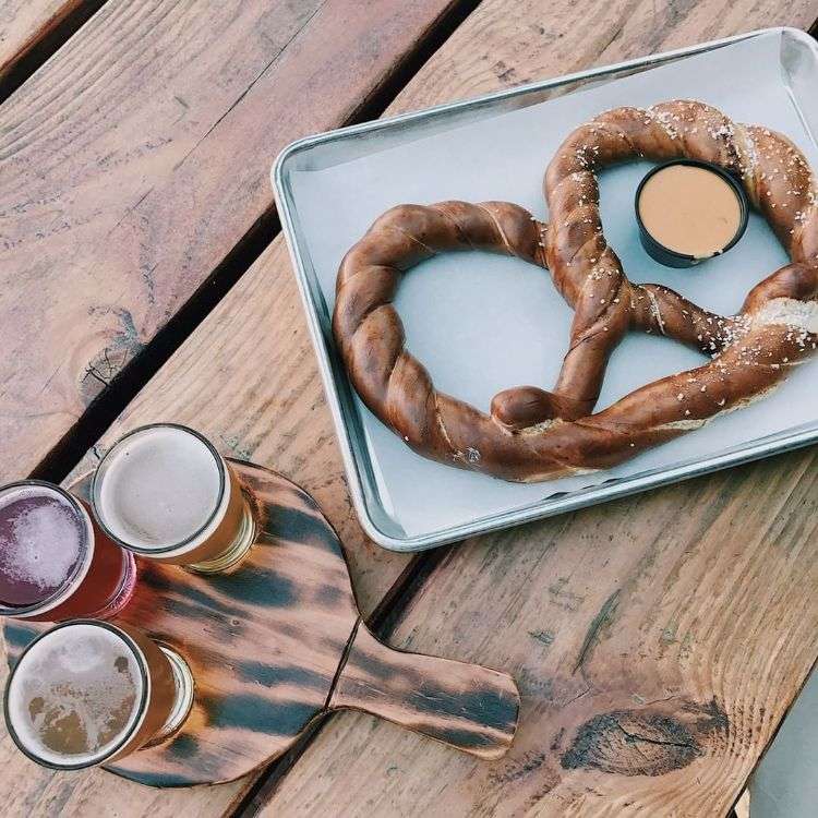 grande pedaço de pretzel copos de cerveja cerveja artesanal tábua de madeira servindo bandeja molho de mostarda