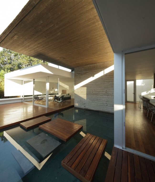 Casa moderna com telhado plano deck de madeira stepping stones interior da parede de vidro do tanque de água