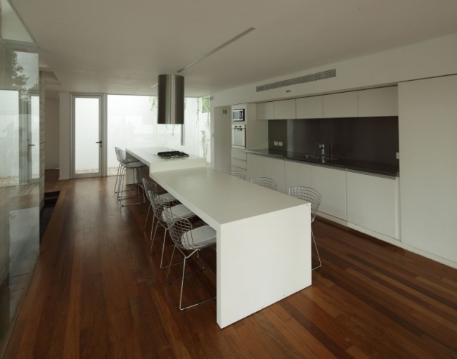 Cozinha equipada, efeito de alto brilho, armários brancos sem puxador, piso de madeira, cadeiras de metal purísticas