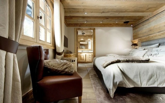 Poltrona de couro, cama de casal, paredes brancas, revestimento de piso de madeira