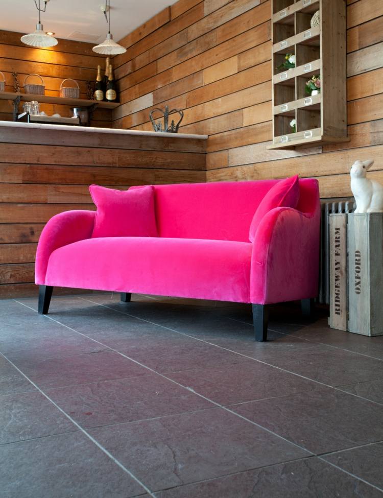 sofá com extravagante bar rosa revestido de placas de madeira na parede