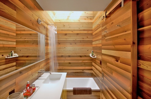 pequena banheira de azulejo de banheiro com parede de aparência de madeira