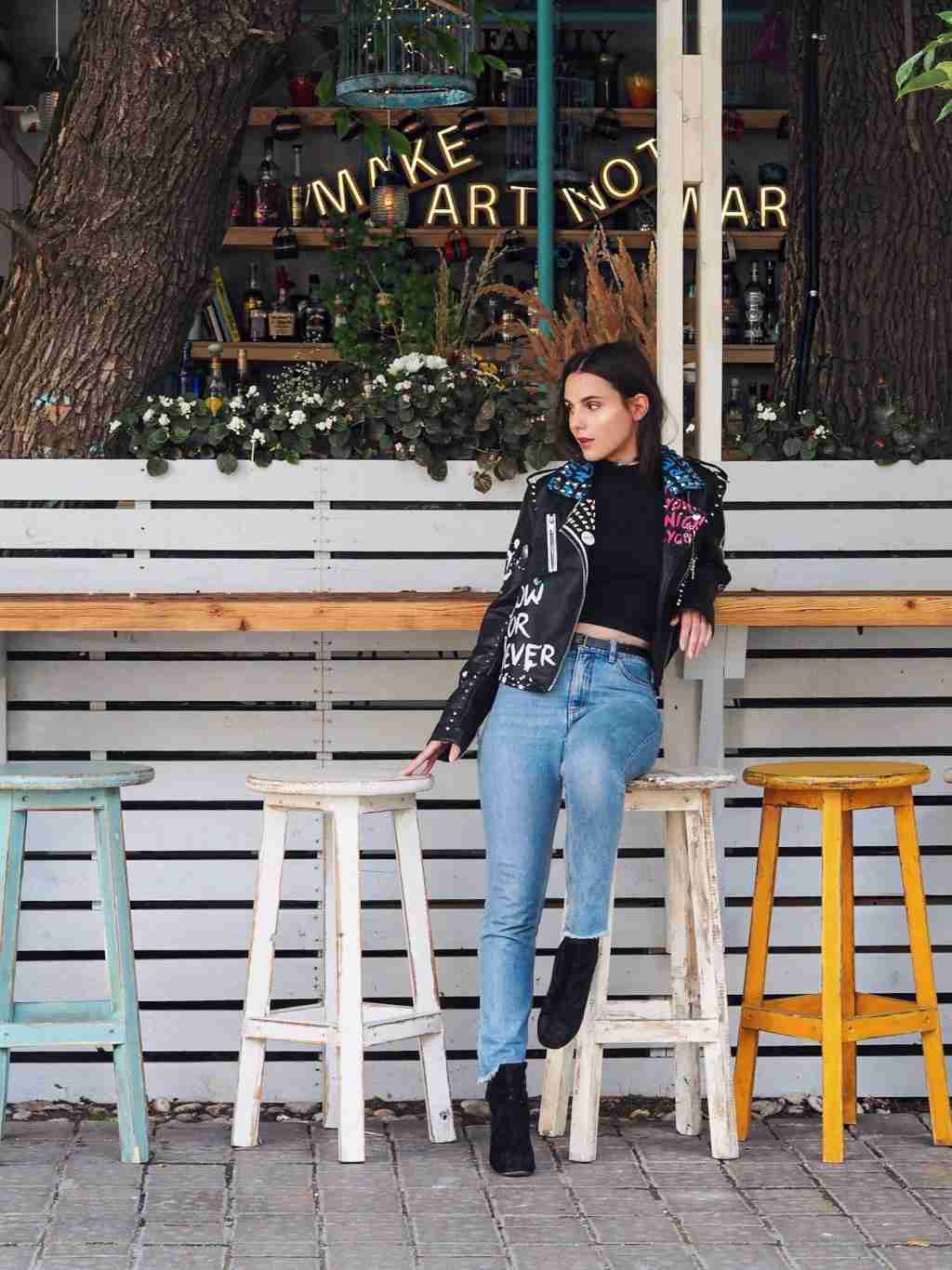 Os jeans da mamãe combinam a jaqueta de couro preta feminina das tendências da moda com botins padronizados