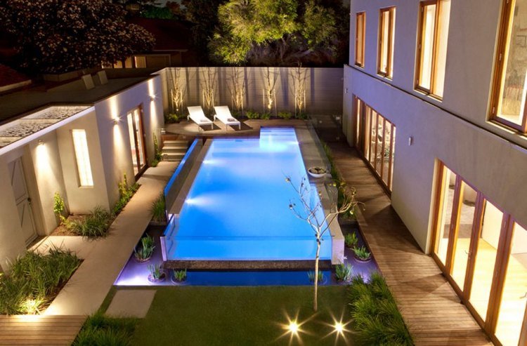 Piscina com parede de vidro com iluminação externa ambiente mágico