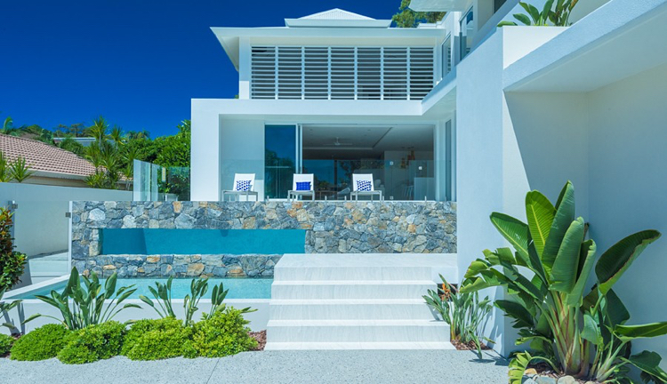 Piscina com revestimento de pedra natural nas paredes externas e janela de visualização de vidro