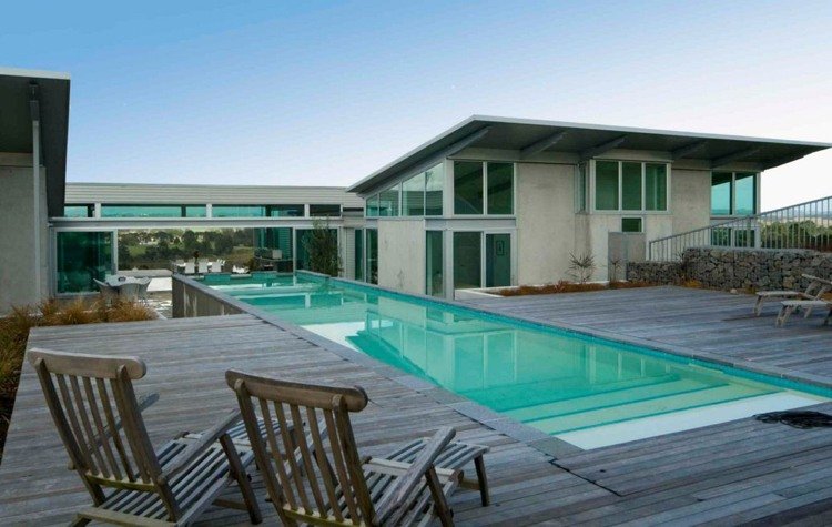 Degraus do terraço de madeira com combinação de concreto e vidro para piscina