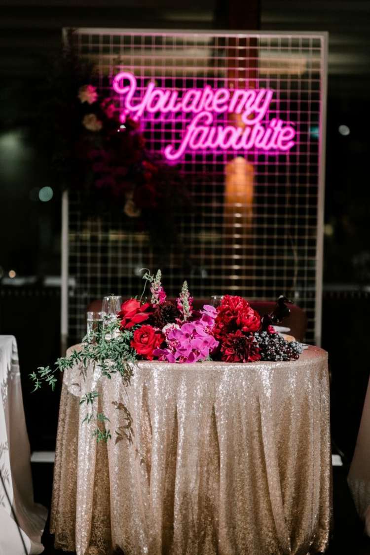 Decoração de casamento glamorosa em ouro com luz de néon rosa no fundo
