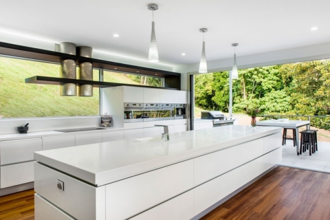 Cozinha com ilha com paredes de vidro branco e terraço adjacente
