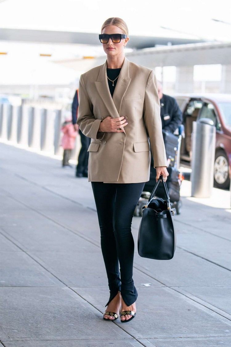 Rosie Huntington-Whiteley vestida com blazer bege, calça preta com uma pequena fenda e sandálias