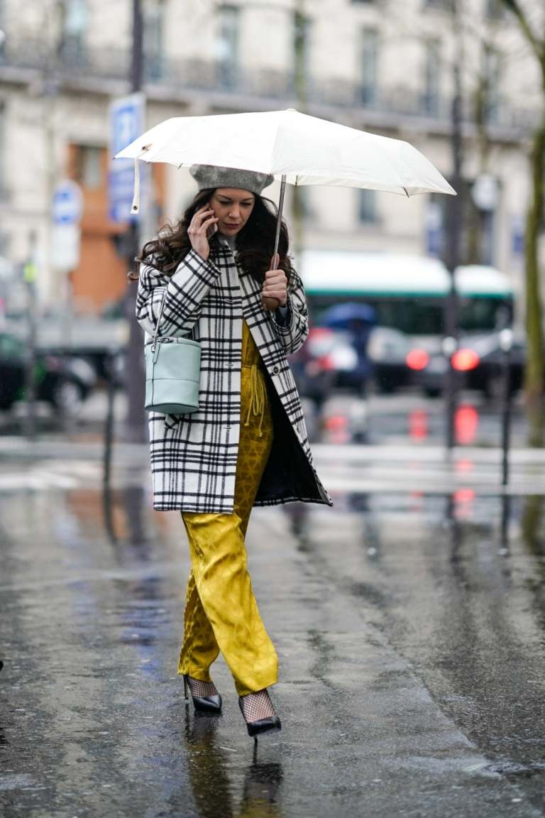 Calça comprida amarela, escarpins e gabardines xadrez como roupa de chuva para mulheres