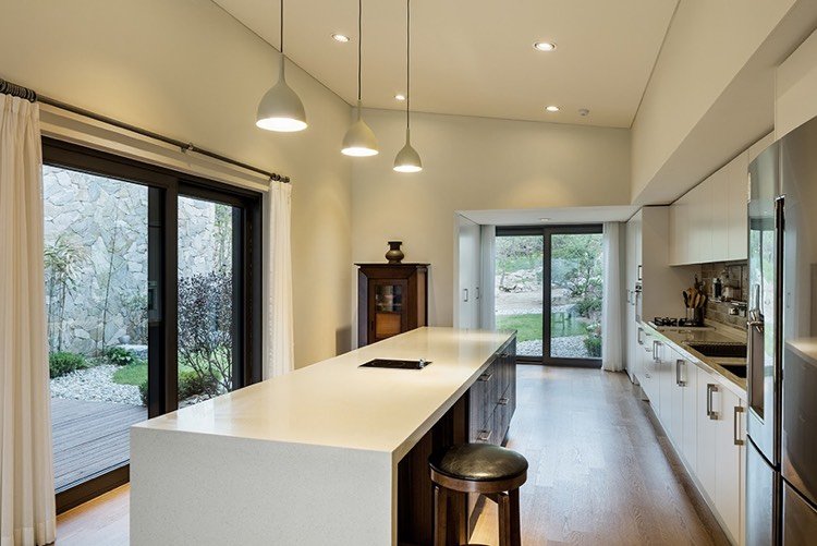 casa de pedra natural-moderno-interior-cozinha-ilha-branco-acesso-jardim