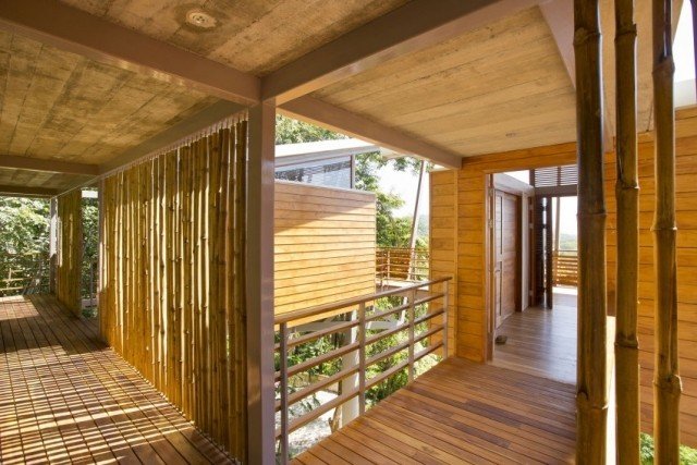Casa de madeira aberta sobre palafitas com varas de bambu com vista para o mar