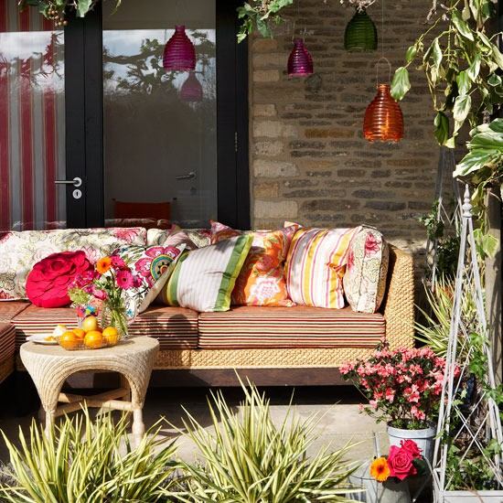 Salão no jardim para relaxar com luzes de vidro coloridas no sofá ensolarado