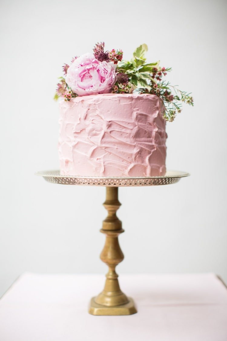 Lindo bolo de casamento rosa com cobertura de creme em um suporte alto