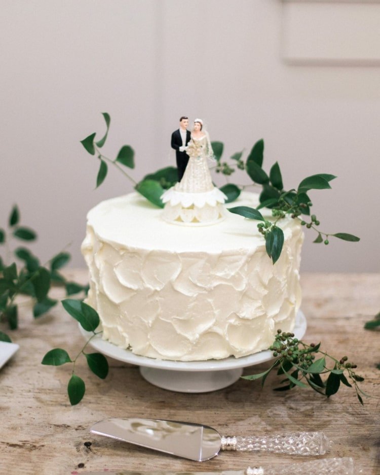 Crie pequenos bolos de casamento simples em um nível com uma figura de bolo e folhagens
