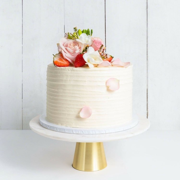 Creme canelado para um bolo de casamento visualmente interessante, mas simples, com flores e morangos