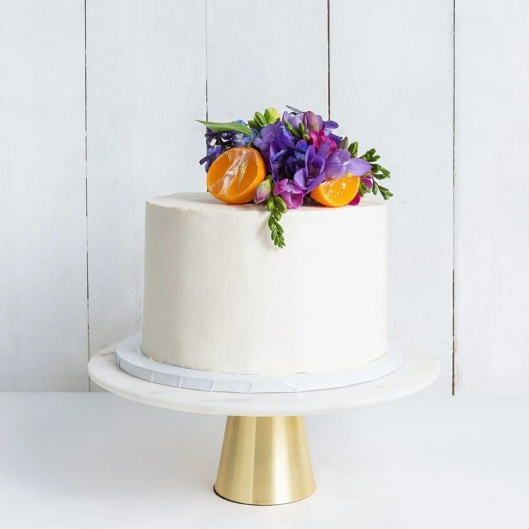 Decoração exótica de bolo com laranjas e orquídeas roxas