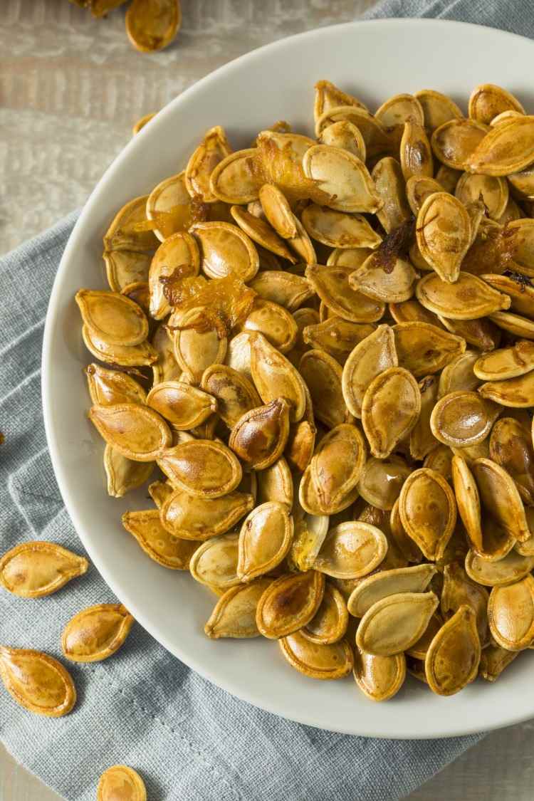 Sementes de abóbora assadas com as cascas em um prato como lanche para quem tem fome