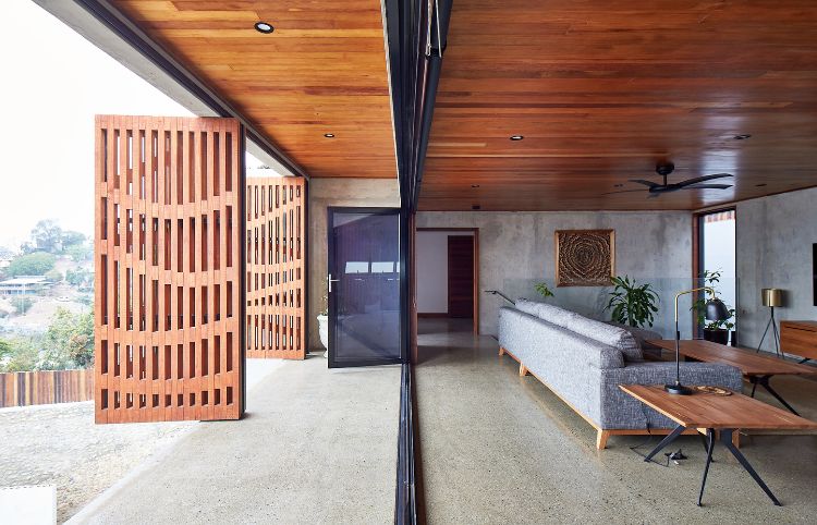casa de design moderno sala de estar sofá mesa de madeira janelas de madeira portas janela lâmpadas concreto piso painéis de madeira