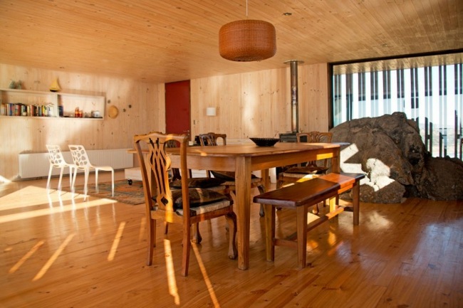 Sala de estar com lareira de pedra, sala de jantar, banco de madeira