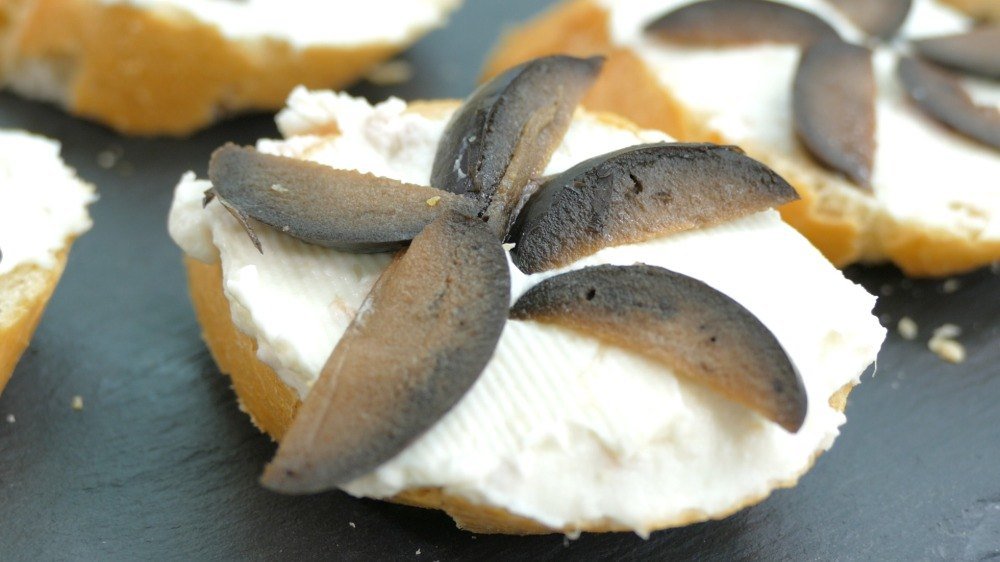 Pedaços de cream cheese com azeitonas como petisco para crianças