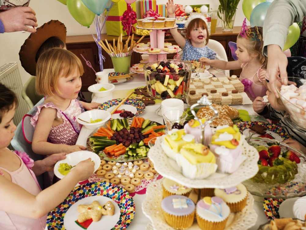 as crianças comemoram seu aniversário com uma mesa cheia de iguarias cuidadosamente preparadas