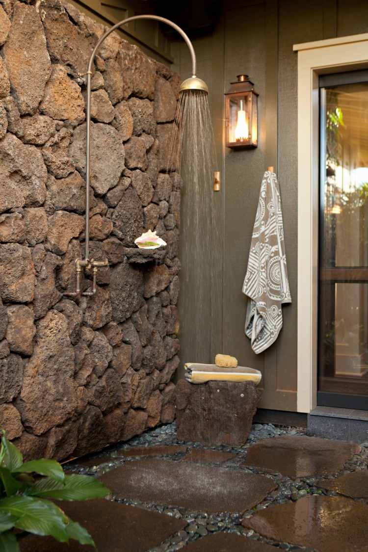 ducha externa com paredes de pedra em estilo rústico com ganchos de assento e lanterna para maior conforto