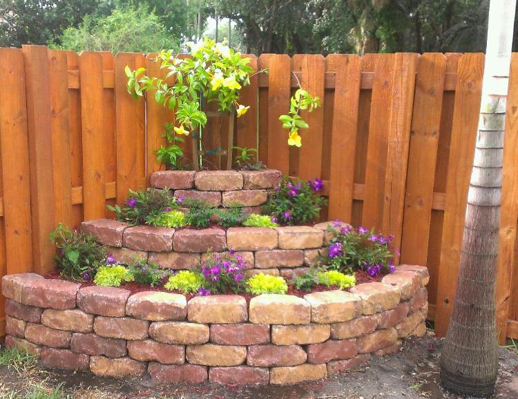 Projeto do canto do jardim canteiro de flores nos tijolos da cerca