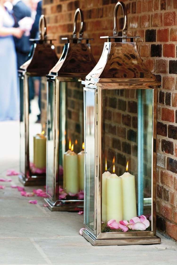 Lanternas de jardim com velas -metal-parede de tijolo grande-fora-folhas de rosa-romântico