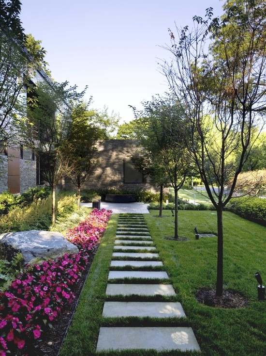 Caminhos de jardim com gramado na fronteira do canteiro de flores com pedras